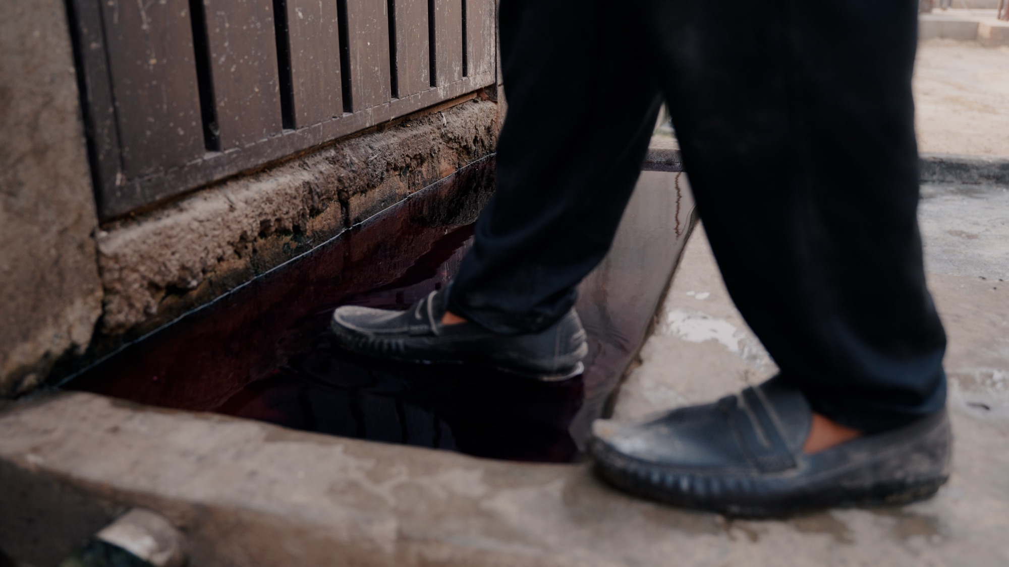A staff member stepping through a disinfectant footbath at the entrance